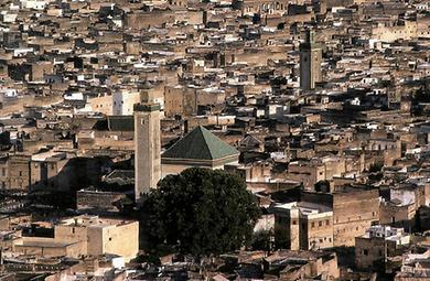 Fes in Marokko ist eine der frühesten islamischen Stadtgründungen und besteht fast ausschließlich aus traditionellen Hofhäusern mit Flachdächern. Das große Zeltdach gehört zur Moschee mit dem massigen Minarett.