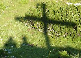 Schatten von Gipfelkreuz mit zwei Personen daneben