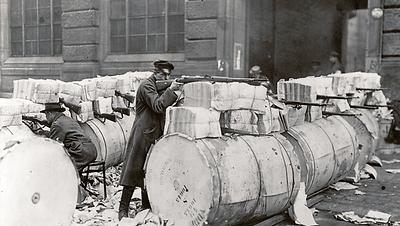 Zeitungspapier dient nicht wie im Bild als Schanze, von der die Spartakisten in Berlin anno 1919 schossen, sondern wer von „Lügenpresse“ spricht, unterstellt dem gedrucken Papier, als „Waffe“ in der öffentlichen Auseinandersetzung zu fungieren