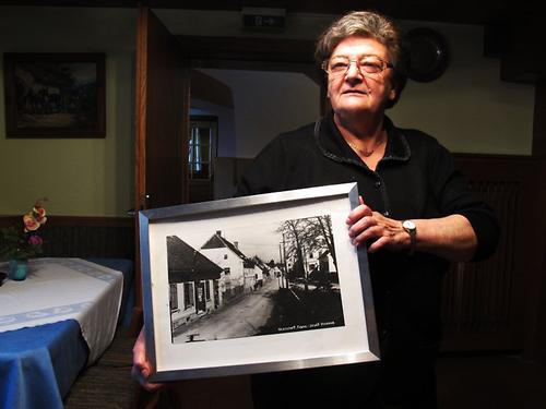 Olga Wurm, erfahrene Gastwirtin an dieser Route, hat ein altes Foto der Straße und zeigt, wo seinerzeit die Fuhrleute ihre Wagen abgestellt haben, um bei ihr einzukehren. (Foto: Martin Krusche)