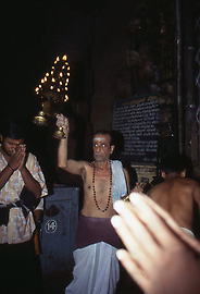 Ein Tempeldiener segnet die Gläubigen mit einem großen Leuchter