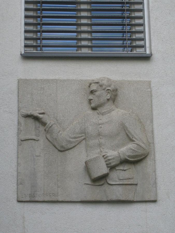 Hauszeichen als Kunststeinrelief 'Anstreicher' von Anton Endstorfer 1952