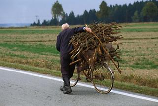 Alter Mann transportiert Holz auf dem Fahrrad