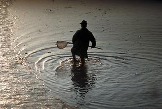 Silhouette eines Fischers mit Fischernetz