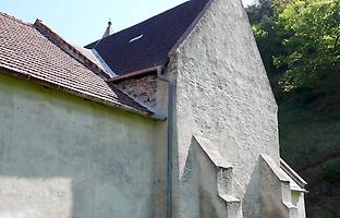 Zwickel zwischen Kirche und Gebäude mit sichtbarer römischer Mauer