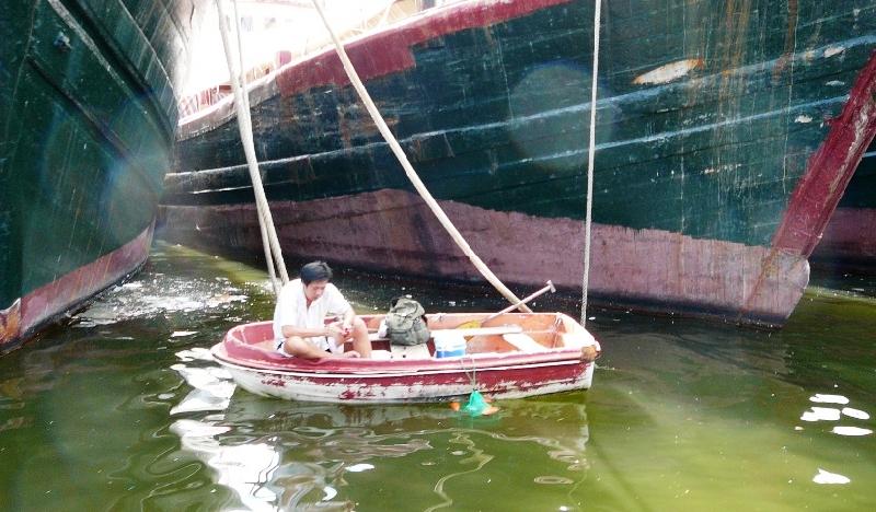 man on a tiny boat between big ones