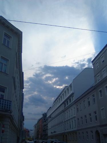 Eine Gasse in Wien: Gewitter nähert sich vom Westen als Wolkengebirge. Darüber die Helligkeit des Sonnenunterganges. Es ist 20 Uhr. Wie in einem Horrorfilm. Nahezu eine halbe Stunde später bricht ein Unwetter aus. Mit schwerem Prasselfregen, Blitz und unendlichen umherrollenden Donner. Auf den Dächern klatschen die Regentropfen. Ähnlich Erbsen die in einem Topf geschüttet werden - Foto: Ernst Zentner - 28. Juli 2020 - 19:59:15