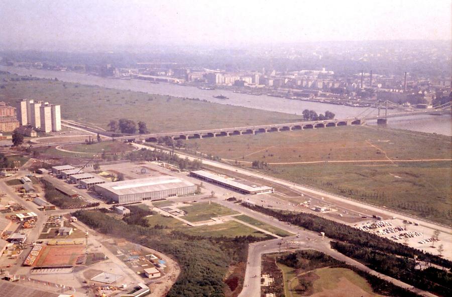 Blick vom Donauturm (Wiener Internationale Gartenschau 1964, heute als Donaupark bekannt) auf das Überschwemmungsgebiet und der als Kettenbrücke gebauten Reichsbrücke (ganz rechts)