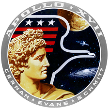 Das offizielle Apollo-17-Emblem, Robert T. McCall/Apollo 17 astronauts, 1972. Sonnen-Gott Apollon und der amerikanische Adler, Mond, Saturn, Andromeda-Galaxie und Weltraum. Das Emblem deutet den Willen der Menschheit an, den Weltraum zu erobern. Mit der Farbe Gold wurde das goldene Zeitalter der Raumfahrt angesprochen - Foto: NASA, Wikimedia Commons - Gemeinfrei?