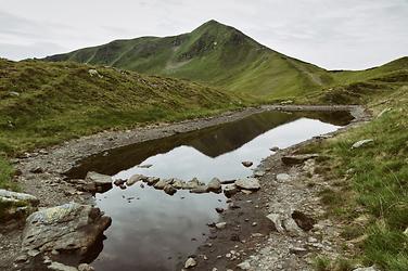 In einem geschmolzenen Restschneefeld spiegelt sich der Kreuzkogel