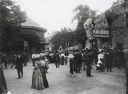 Belebte Straße im Volksprater mit dem Flohzirkus und dem Calafati. Wien. Glasdiapositiv um 1910.