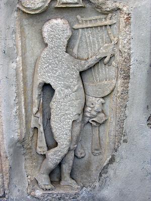 Leider wurde bei dieser Grabstele der dargestellte Musiker fast vollständig heruntergestemmt und abgeflacht, damit die Stele besser im frühmittelalterlichen Turm auf dem Seggauer Berg als Mauerstein verwendbar war. Das Musikinstrument ist unbeschädigt geblieben. Heute ist die Stele wieder sichtbar in der Außenmauer von Schloss Seggau eingemauert