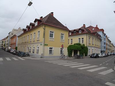 Der im Foto an den Fassaden gelb gefärbte, zweigeschossige Schützenhof ist das älteste Gebäude in der gesamten Umgebung der Herz-Jesu-Kirche. Im Gegensatz zu den sonst meist dreigeschossigen, geschlossenen Blockrandverbauungen aus der Zeit des Historismus war der Schützenhof ursprünglich ein Solitärbau auf freiem Feld