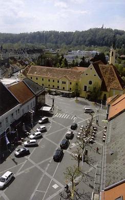 Blick auf den Hauptplatz von Leibnitz Richtung Frauenberg mit Wallfahrtskirche vom Rathausturm. Der nach den Kardinalpunkten orientierte Raster des neu nach Plänen von Max Stoisser gestalteten Hauptplatzes zeigt, dass er nach Südwesten zur Kirche auf dem Frauenberg ausgerichtet ist, wo dir Reste röm. Tempel stehen.