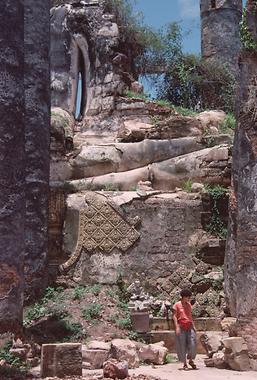Oben im Bild sieht man die Reste einer zerstörten riesigen Buddha-Statue bei den Königsgräbern. Man beachte die kleine Person (Ingrid) im Verhältnis zu den Resten der Skulptur!