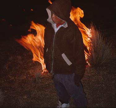 Junger Bursche aus Lagunas vor brennendem Ichú-Grasbüschl.