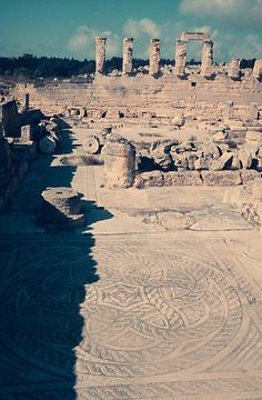 Mosaikrosette im Haus Jasons des Großen in Cyrene; dahinter das hellenistische Gymnasium mit Hermen-Dekor.