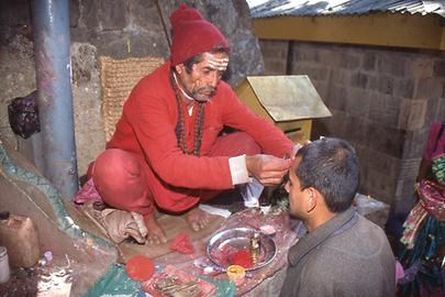 A Brahmin makes a red sign of blessing on the forehead of a pilgrim. His own forehead painting indicates that he is a follower of Shiva