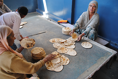 Women lay flatbread on top of each other for distribution