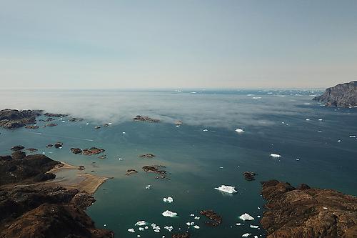 Der Ammassalikfjord, Ostgrönland. Die Schichtbewölkung in tiefen Lagen deutet auf eine Inversionsschicht hin, die den Luftaustausch mit höheren Schichten reduziert