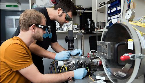 Zwei Forscher aus dem Team arbeiten im Labor an der Aufhängung des Pendels in einer Vakuumkammer