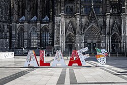 Vor der Fassade des Kölner Doms sind rote und weiße, ca. 1,50&nbsp;m hohe Buchstaben aufgestellt, die das Wort „Alaaf“ bilden.