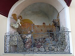 Die im unteren Teil von einem Rankengitter abgeschlossene Nische der Ölberggruppe. Die Jesusfigur blickt zu einem über ihm schwebenden Engel, während Jesus’ Jünger hinter ihm schlafend liegen. Die Rückwand der Nische ist mit der Darstellung eines großen, sandfarbenen Gebäudes bemalt.