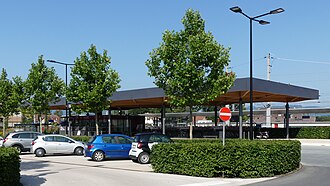 Die Westseite: unter dem Dach links die Bäckerei, rechts der Fahrradständer und im Vordergrund der Parkplatz