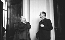Dieses Bild zeigt auf der linken Seite Hanns Eisler, rechts Bertolt Brecht im Gespräch. Wie so oft, Brecht hält in seiner linken Hand eine Zigarre, Eisler hat einen Mantel an und steht mit verschränkten Armen. Das Bild selbst ist undatiert, muss aber nach 1950 aufgenommen worden sein und stammt aus dem deutschen Bundesarchiv.