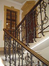 Ornate staircase, a landing with an interior door and window, staircase continuing up