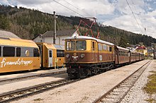 Die in den Farben gold und braun neu lackierte Lokomotive E10 steht mit einer Ötscherbär – Garnitur im Bahnhof Mariazell