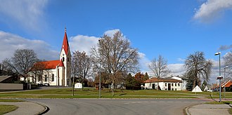 Ortszentrum mit röm.-kath. Pfarrkirche. Davor eine Grünanlage mit dem Kriegerdenkmal