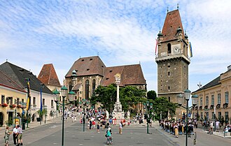 Perchtoldsdorfer Marktplatz: links die Martinskapelle, mittig die Pfarrkirche, rechts der Wehrturm und im Vordergrund die Dreifaltigkeits-(Pest-)säule