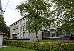 Foto des Rathauses zeigt einen schachtelförmigen Betonbau mit großen Fenstern auf den Längsseiten