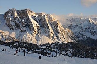 Die nordwestlichen Steviawände und rechts im Hintergrund die Sellagruppe von der Aschgleralm aus betrachtet. Die Pela de Vit teilt sich von links nach rechts im O.-, Mittel- und SW.-Gipfel