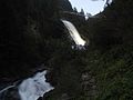 Beleuchteter Wasserfall in der Dämmerung mit der neuen Hängebrücke im Hintergrund